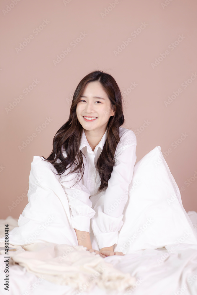 Happy Asian girl sitting on white modern bed and relax at home. Happy Asian girl sitting on white modern bed and relax at home.