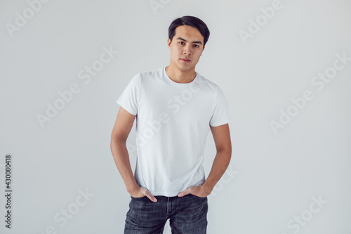 Attractive asian man in white t-shirt stands on white background.