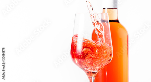 Rose wine pouring out of the bottle, white bakcground. Rosado, rosato or blush wine tasting in wineshop, bar concept. Copy Space photo