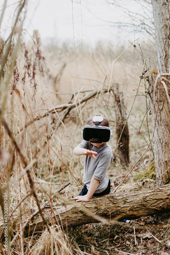 Little girl in a forest is having fun while using some VR headsets outdoor