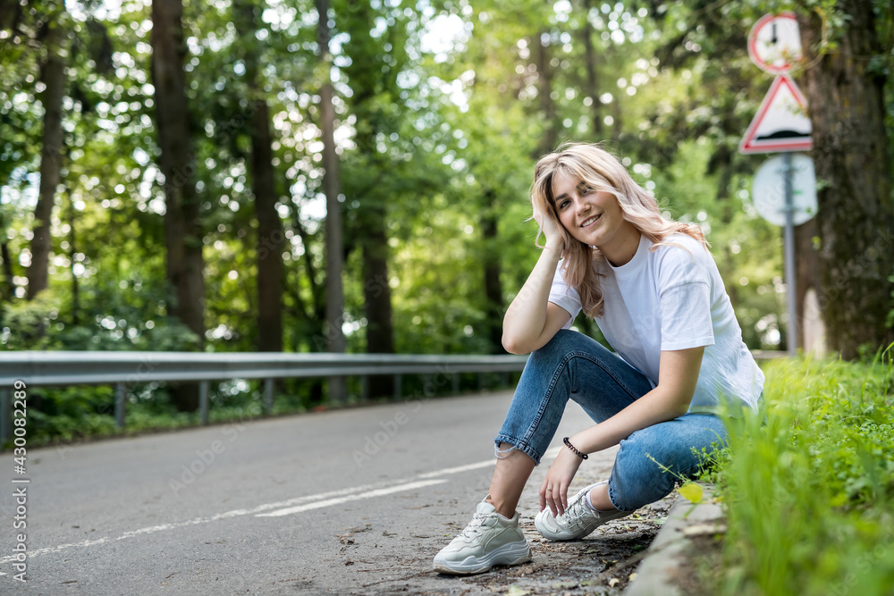 beautiful slim girl with wearing casual cloth sitting on the road in the woods, summer day