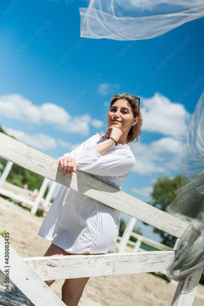 pretty girl enjoy sunny summer day near lake in white gazebo