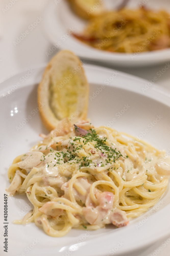 Italian pasta spaghetti Carbonara with fried bacon, parmesan cheese and parsley on white plate. Restaurant food concept
