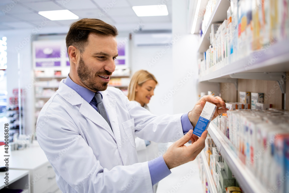 Pharmacist working in pharmacy store and and holding medicine.