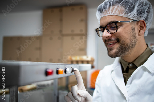 Factory worker switching off industrial machine after work.