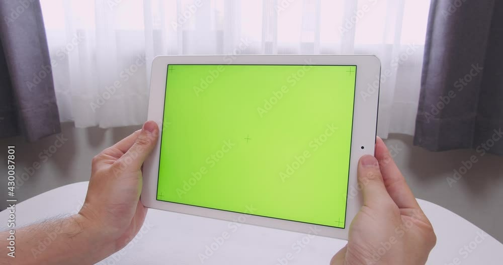 Man hands holding Green Screen (chroma key) with cross sign smart tablet in his room in the day time. Casual, simple and stylish design concept. The angle is a little bit diagonal Man hands holding Green Screen (chroma key) with cross sign smart tablet in his room in the day time. Casual, simple and stylish design concept. The angle is a little bit diagonal