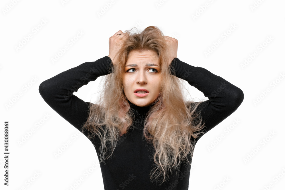Scared and worried young blonde woman panicking, holding hands on head and look nervous, standing over white background