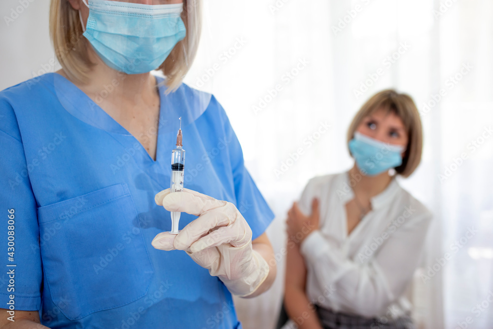 Doctor giving an injection to the patient. Attractive hispanic female patient getting vaccine on her arm by a doctor in hospital. Doctor holding syringe making covid 19 vaccination injection dose Doctor giving an injection to the patient. Attractive hispanic female patient getting vaccine on her arm by a doctor in hospital. Doctor holding syringe making covid 19 vaccination injection dose