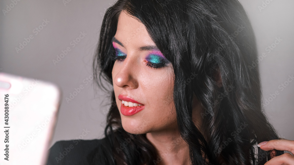Beautiful young girl with dark long hair shooting with a bright make up. Making selfie with a phone. Beautiful young girl with dark long hair shooting with a bright make up. Making selfie with a phone.