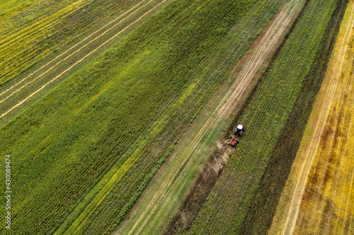 Aerial view of tractor plowing field after sunflower harvest