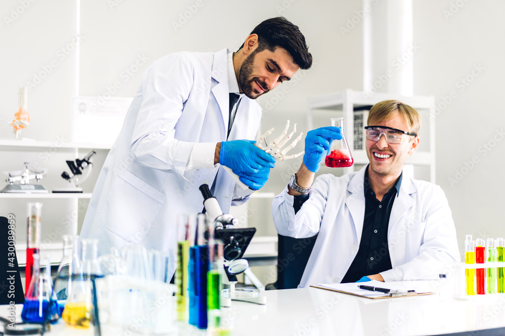 Professional two scientist man research and working doing a chemical experiment while making analyzing and mixing liquid in test tube.Young science man dropping sample chemical on glass at laboratory Professional two scientist man research and working doing a chemical experiment while making analyzing and mixing liquid in test tube.Young science man dropping sample chemical on glass at laboratory