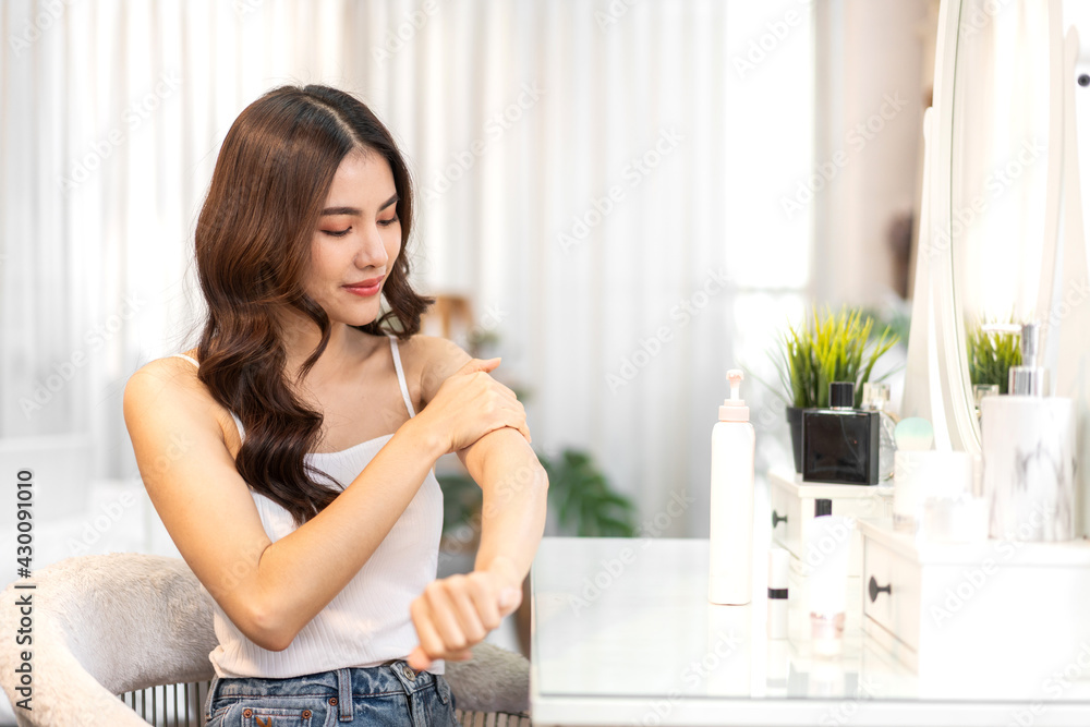 Smiling of young beautiful pretty asian woman clean fresh healthy white skin looking at mirror.Asian beauty girl touching on her hand and applying cream at home.spa and beauty concept Smiling of young beautiful pretty asian woman clean fresh healthy white skin looking at mirror.Asian beauty girl touching on her hand and applying cream at home.spa and beauty concept