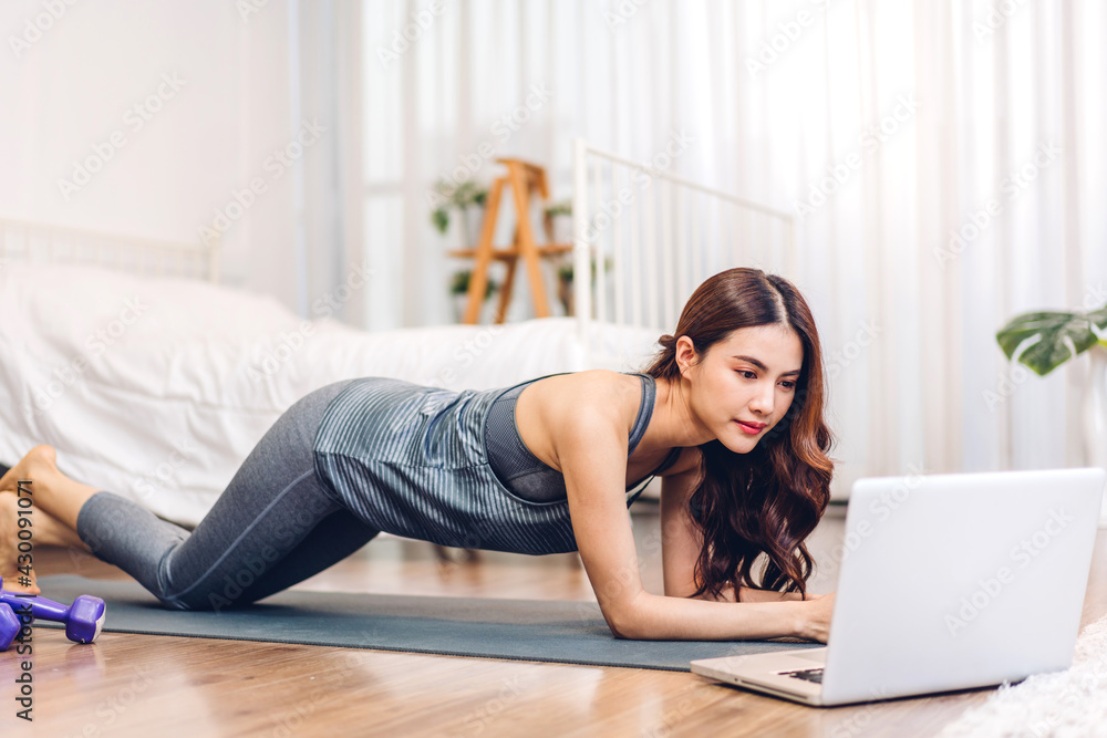 Portrait of sport asian woman in sportswear sitting relax and practicing yoga and do fitness exercise with laptop computer in bedroom at home.Diet concept.Fitness and healthy lifestyle Portrait of sport asian woman in sportswear sitting relax and practicing yoga and do fitness exercise with laptop computer in bedroom at home.Diet concept.Fitness and healthy lifestyle