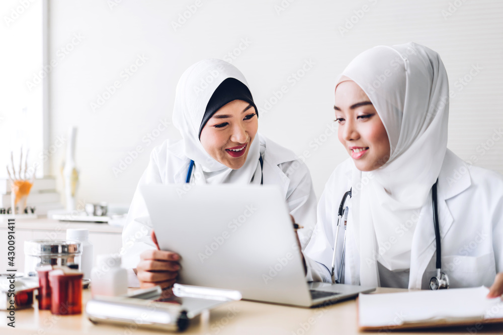 Professional medical two muslim asian woman doctor team with stethoscope in uniform working with laptop computer on desk in hospital.healthcare and medicine