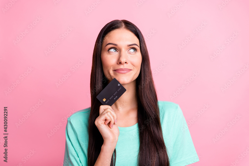 Photo of young attractive cheerful girl look copyspace dream about money hold credit card isolated on pink color background Photo of young attractive cheerful girl look copyspace dream about money hold credit card isolated on pink color background