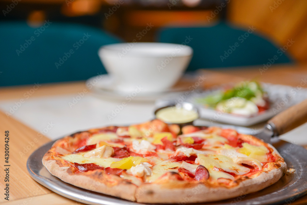 Margherita Pizza served in restaurant or pizzeria. Photo with blurred background. Traditional Italian cuisine concept.