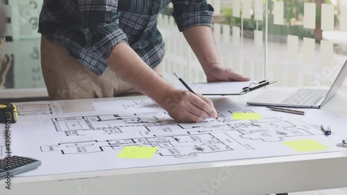 Architectural building design and construction plans with blueprints, Young man was designing a building or architecture with a ruler, pen, pencil, tape measure, architect hat and other equipment.