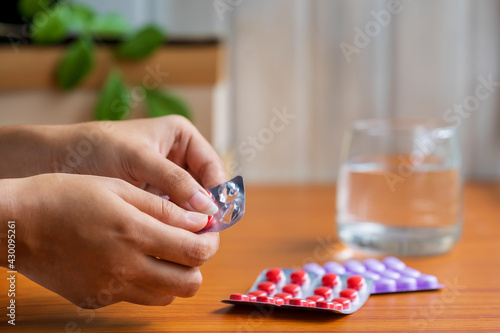 Woman Taking Pills or Medicine. A female person taking medicines or antibiotic tablets with a glass of water. Concept for sick at home treatment and medication, covid-19 immunity booster, vitamins.