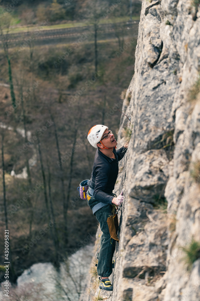 Male climber anticipates his next move while climbing vertical wall. Male climber anticipates his next move while climbing vertical wall.