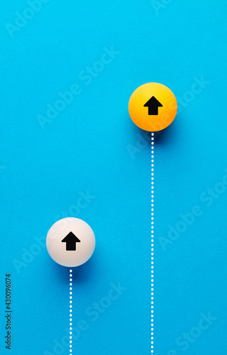 White and orange table tennis balls are racing with each other on blue background.