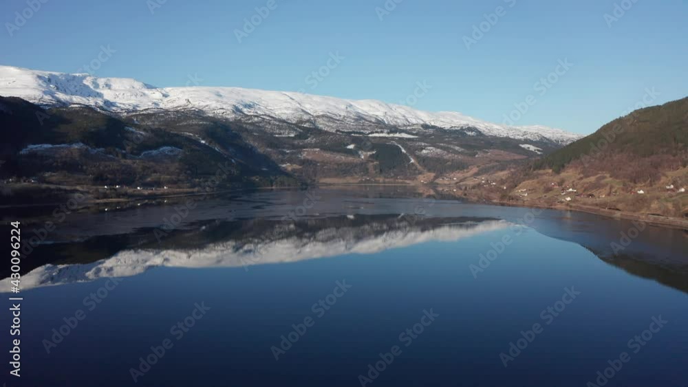 Vangsvatnet lake in Vossevangen shown with Bulken and Vosso river in background - Aerial overview with snow capped mountain tops Vangsvatnet lake in Vossevangen shown with Bulken and Vosso river in background - Aerial overview with snow capped mountain tops