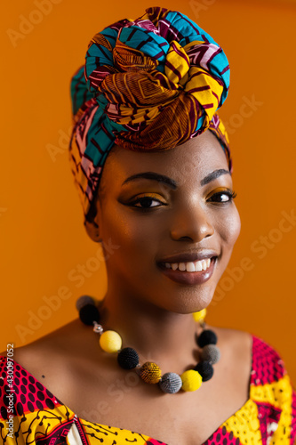 Vertical photo of a black woman in a bright turban and with a necklace around her neck. photo