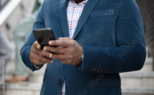 African business man using mobile outside. Focus is on hands.