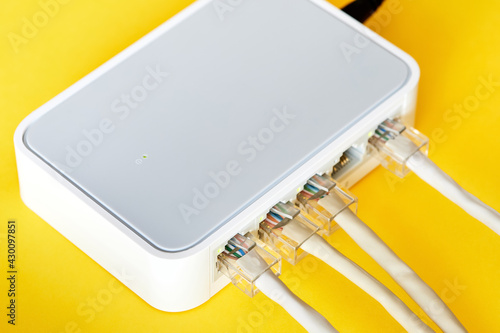 Ethernet cables connected to Desktop Switch or routerboard on a yellow background. Close-up, selective focus photo