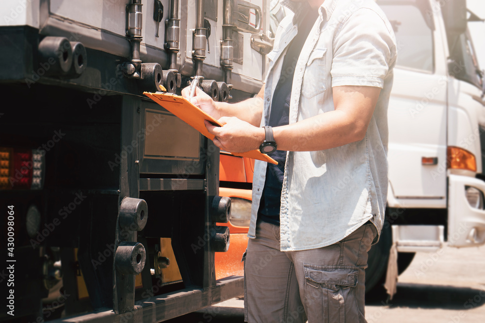 Truck Driver holding Clipboard Checking Maintenance and Safety Steel Door of Trailer Truck.