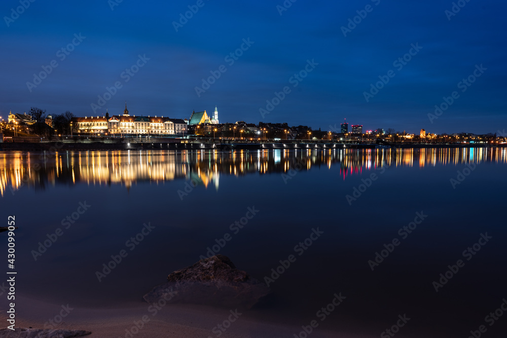 Nocne zdjęcie mostu i widok na stare miasto w Warszawie