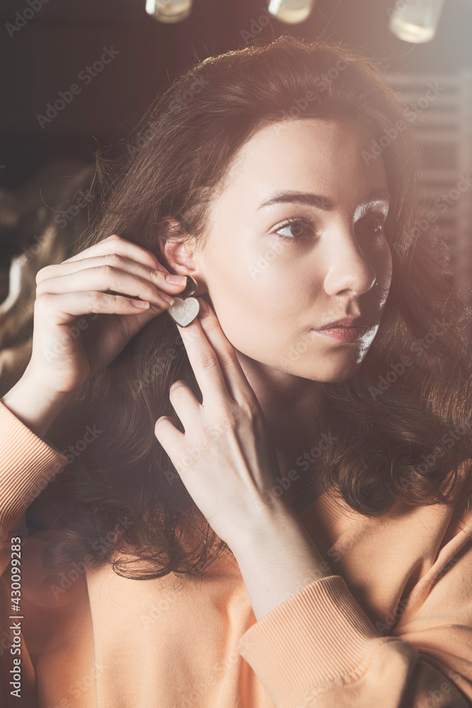 Fototapeta premium close up of beautiful woman puts on heart shaped earrings