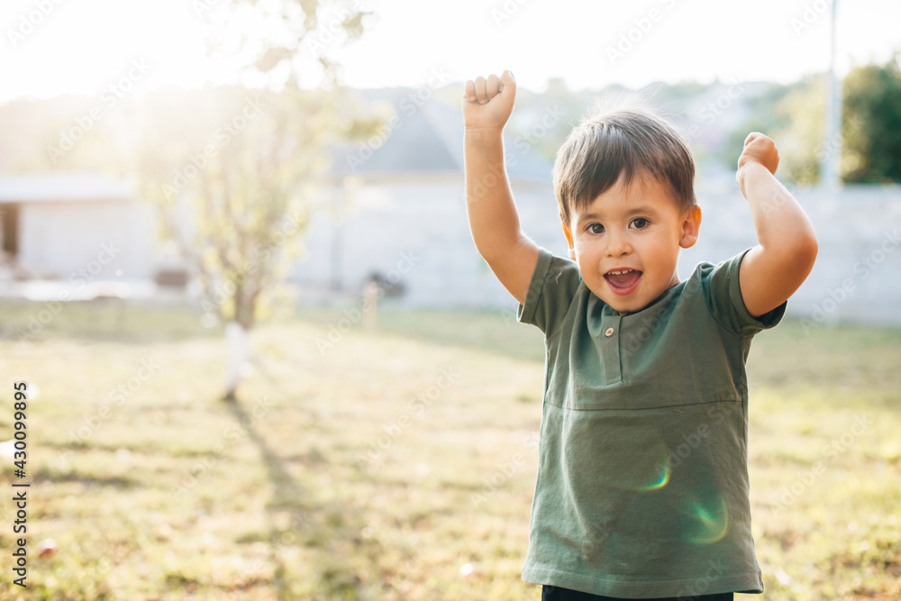 Small caucasian boy is gesturing the win sign posing in a garden at home Small caucasian boy is gesturing the win sign posing in a garden at home