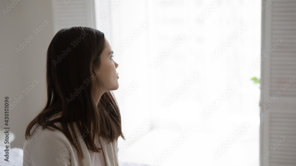 Thoughtful millennial young woman looking away at window at home. Pensive teenage girl lost in thoughts thinking over problem solving, feeling sad, frustrated, lonely, depressed. Copy space Thoughtful millennial young woman looking away at window at home. Pensive teenage girl lost in thoughts thinking over problem solving, feeling sad, frustrated, lonely, depressed. Copy space
