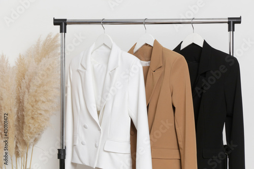 Corner in fashion atelier with fashionable tailored blazers hanging on a rack. Modern premium quality hand made woman's fashion. photo