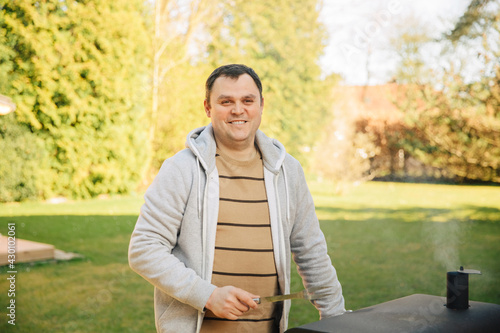 Man smiles and is happy while barbecuing in the garden. Man prepares the grill in the garden. 