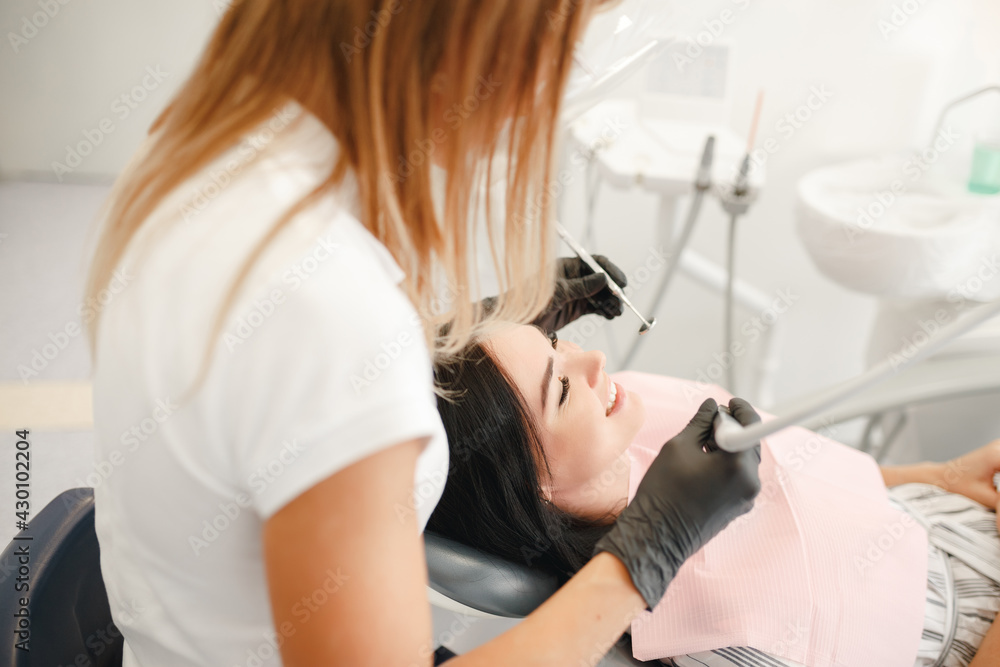 Woman dentist working at her patients teeth. At the dentist office, examination.Dentist working in dental clinic with patient in the chair.... Woman dentist working at her patients teeth. At the dentist office, examination.Dentist working in dental clinic with patient in the chair....