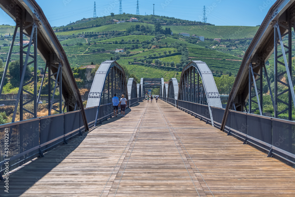 View at the metallic bridge over Douro river on the Peso da Regua downtown, with tourist people strolling