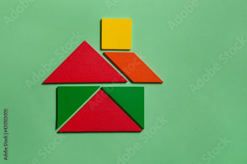 House of colorful tangrams in green background 