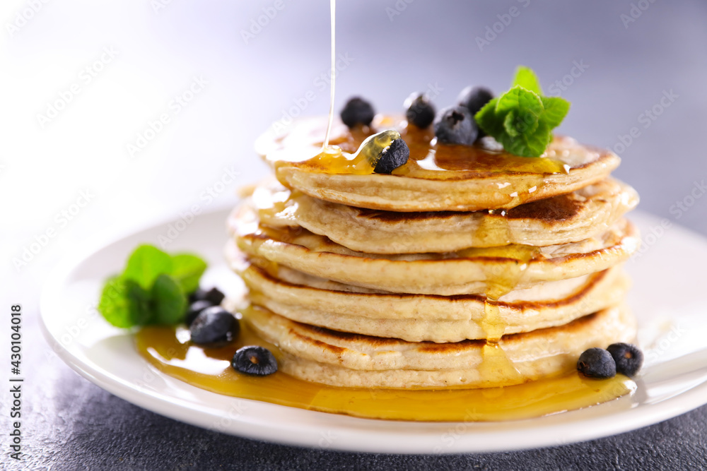 pile of pancake with pouring syrup
