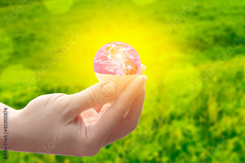 solar energy icon, renewable energy signs, ecology concept,environmental care,lamp in the form of the planet earth in hand of a person on green natural background,Element of the image provided by NASA