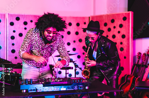 Bild auf Leinwand Young happy people playing music with dj mixer and saxophone in house studio - Y