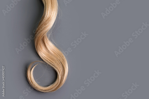 Φωτογραφία Curly blonde hair on grey background