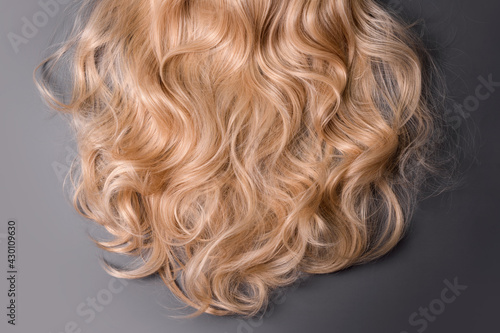 Blonde hair texture. Wavy long curly blond hair close up as background. Hair extensions, materials and cosmetics, wig, hair care. Hairstyle, haircut or dying in salon.