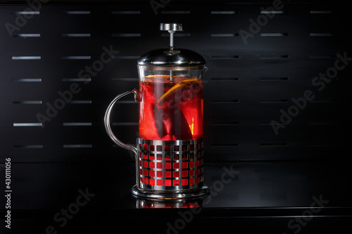 Citrus tea with cinnamon in a teapot on a black background