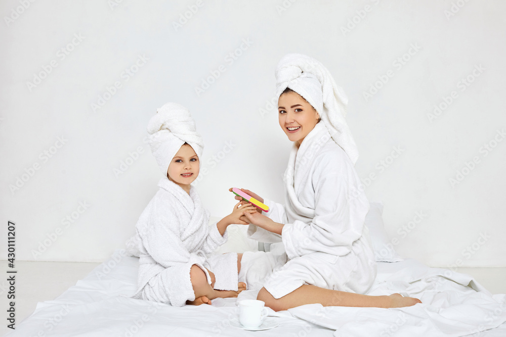 mother and her daughter holding nail file and making manicure mother and her daughter holding nail file and making manicure