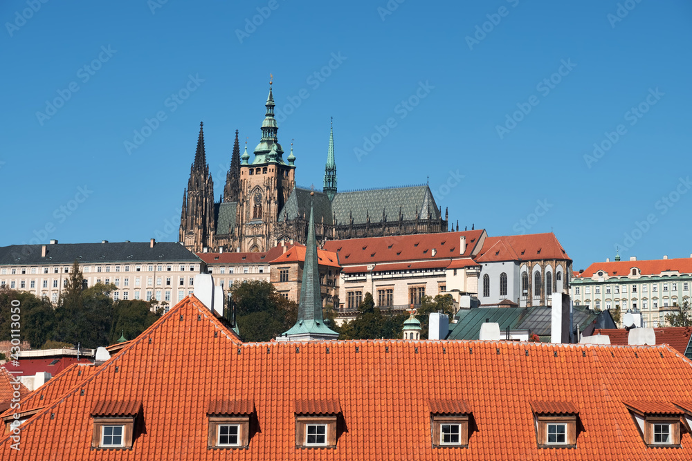 St. Vitus Cathedral and Prague Castle with orange roofs of historic buildings of Mala Strana on a bright Summer day in Prague, Czech Republic. Blue sky, bright sunlight. St. Vitus Cathedral and Prague Castle with orange roofs of historic buildings of Mala Strana on a bright Summer day in Prague, Czech Republic. Blue sky, bright sunlight.