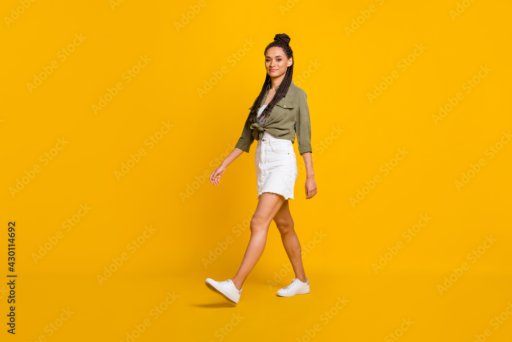 Full length profile side photo portrait of woman walking isolated on vivid yellow colored background