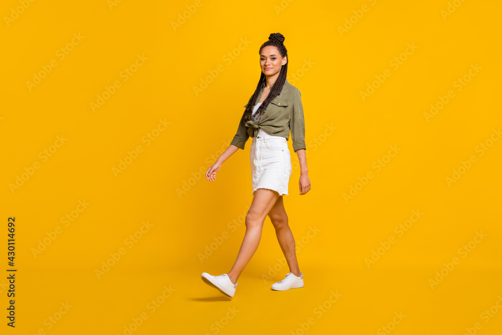 Full length profile side photo portrait of woman walking isolated on vivid yellow colored background Full length profile side photo portrait of woman walking isolated on vivid yellow colored background
