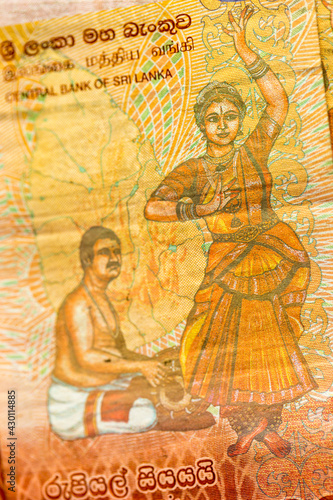 Vertical macro detail of the reverse side of 100 Sri Lankan Rupees LKR bill banknote (Sri Lanka Dancers series) showing a traditional mridangam drummer and bharatanatyam dancer photo