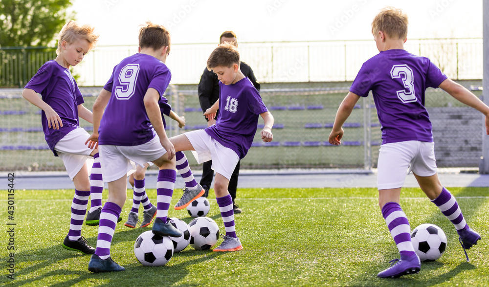 Happy young boys running and kicking the soccer ball on training. Group of  school kids in purple shirts practicing football at the stadium. Kids  Football Jersey Uniforms Stock Photo | Adobe Stock